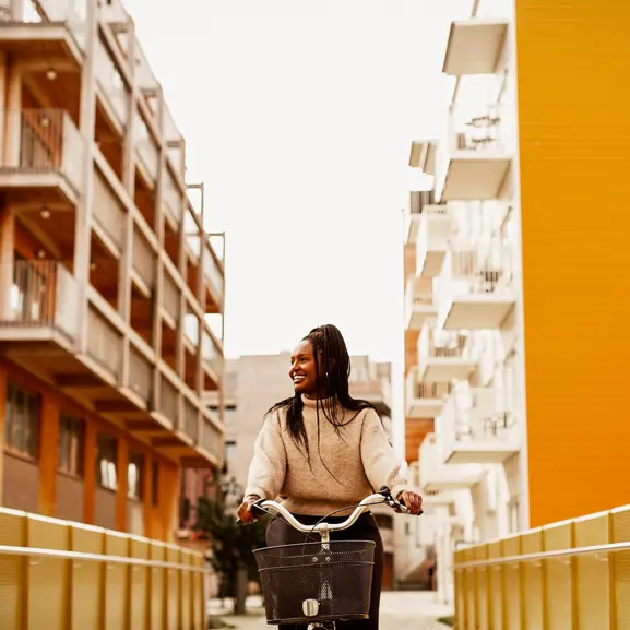 Glad kvinna cyklar orange hus.