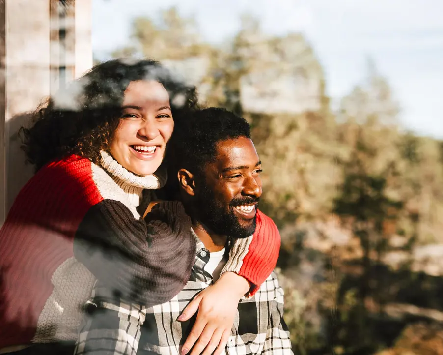 Ett glatt par vid ett fönster i en stuga i skogen.