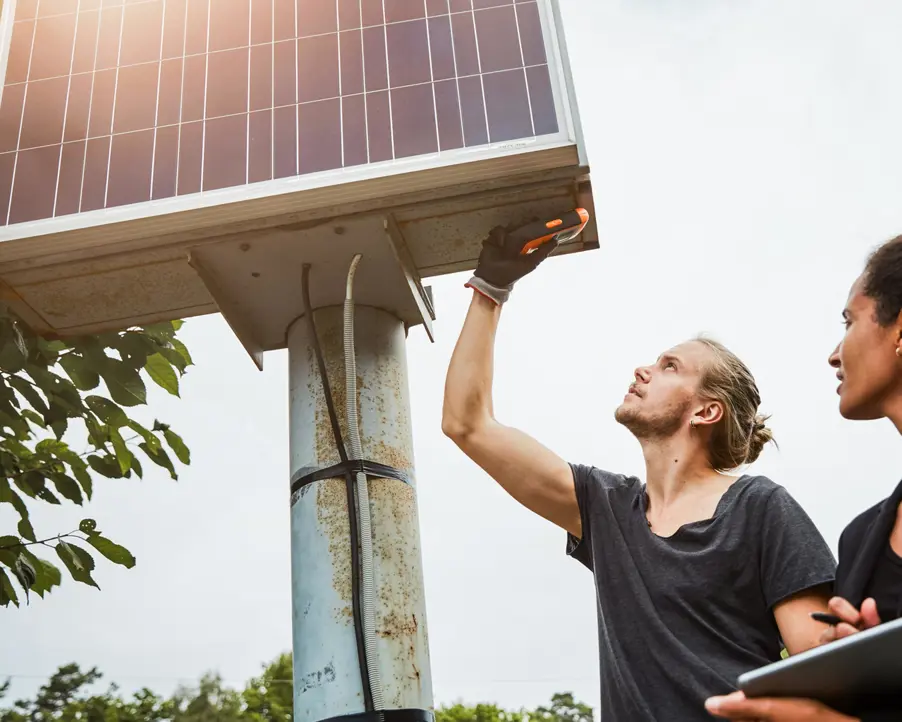 Två unga människor mäter på solpaneler.