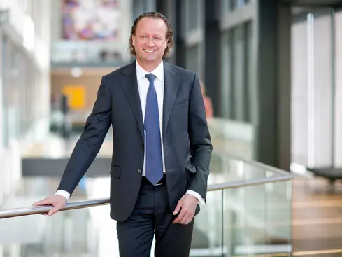 Affärsman i kostym står i en modern kontorsmiljö med glasräcken